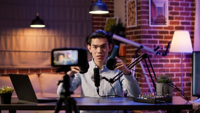Asian influencer filming headphones review on podcast episode